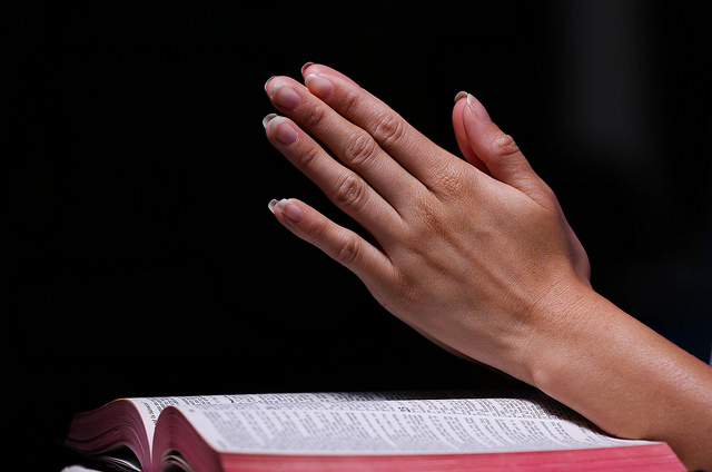 Hands Praying Over Bible